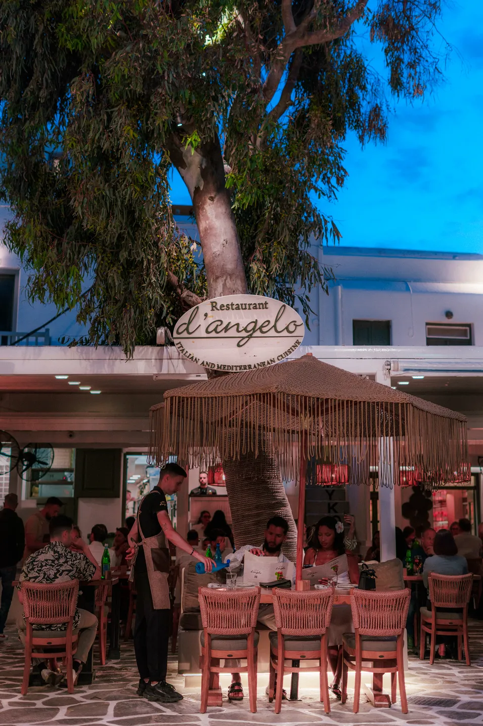 d'angelo restaurant sign at dusk with waiter serving guests